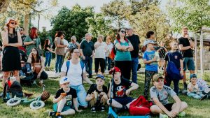 A diverse group of people enjoying a sunny day at an outdoor community event in a park setting.